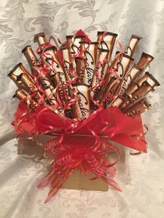 a vase filled with chocolates and wrapped in red ribbon on top of a table