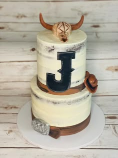 a three tiered cake with the letter j on it's side and an antelope topper