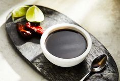 a cup of coffee on a plate with spoons and lime wedges next to it