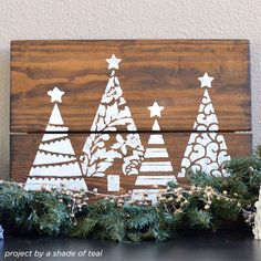 a wooden sign decorated with christmas trees and snowflakes on top of a table