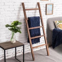 a ladder leaning against a brick wall next to a small table with a potted plant on it