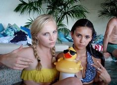 two beautiful women sitting next to each other in a pool with a rubber duck toy