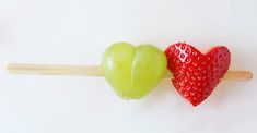 an apple and strawberry shaped lollipops are on a toothpick together