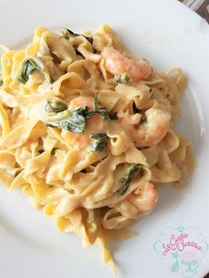 pasta with shrimp and spinach in a creamy sauce on a white plate, ready to be eaten