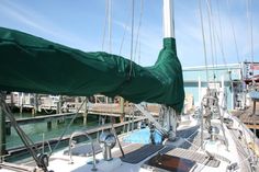 a sailboat with a green tarp on it's side in the water