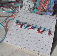 an artistic card with red, white and blue string attached to it on the ground