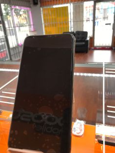 a cell phone sitting on top of an orange table in a room with glass walls