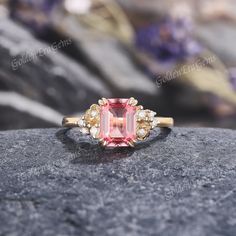 a pink tourmaline and white diamond ring on top of a rock