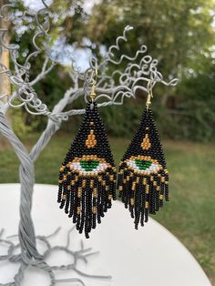 a pair of black beaded earrings hanging from a tree