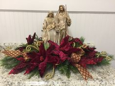 a christmas arrangement with poinsettis and decorations on a marble countertop in front of a white wall