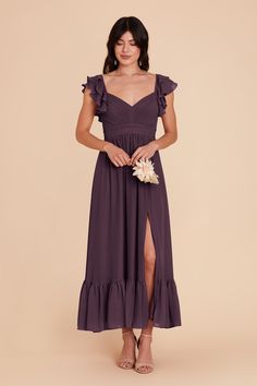 a woman wearing a purple dress with ruffles on the shoulders and side slit