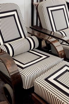 two chairs sitting next to each other on top of a wooden floor covered in black and white striped fabric