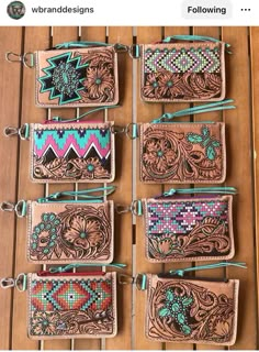 six wallets with different designs on them sitting next to each other in front of a wooden table