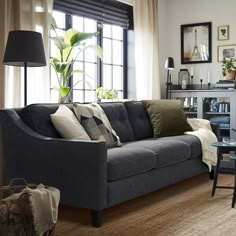 a living room filled with furniture and a lamp on top of a wooden table in front of a window