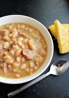 a white bowl filled with beans next to a piece of cheese