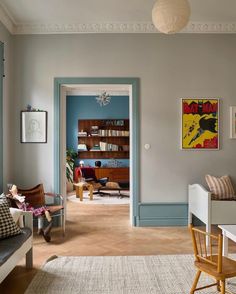 a living room filled with furniture and a painting on the wall next to a doorway