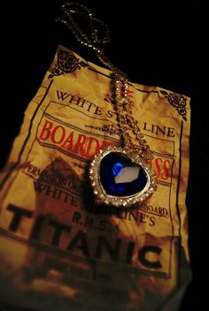 a necklace with a blue tear hanging from it's side on top of a bag