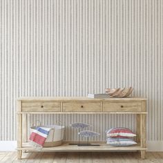 a wooden table with two pillows and an umbrella on it in front of a striped wallpaper