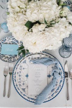 the table is set with blue and white plates, silverware, and napkins