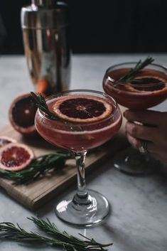 two glasses filled with blood orange and rosemary garnish