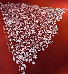 an intricately designed red table cloth with white designs on the top and bottom edge