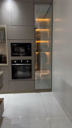 an empty kitchen with two ovens in the wall and white tile flooring on the walls