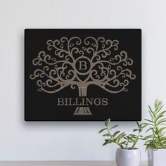 a black and gold canvas with the words blings on it next to two potted plants