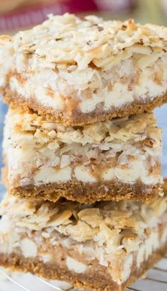 three dessert bars stacked on top of each other with nuts and coconut in the middle