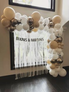 balloons and streamers are hanging from the ceiling in front of a window that reads bikinis & martinis