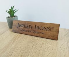 a wooden sign sitting on top of a table next to a potted plant