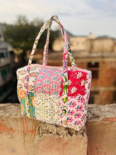 a multicolored purse sitting on top of a stone wall