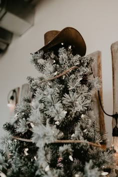 Flocked Christmas tree decorated with lasso, lights, and a cowboy hat Christmas Tree Decorations Western, Country Theme Tree, Cowboy Hat Christmas Tree Topper, Western Tree Ideas, Cowboy Hat Tree Topper, Christmas Western Decor, Country Christmas Theme Party, Western Xmas Tree