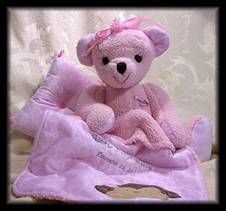 a pink teddy bear sitting on top of a blanket