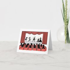 there is a card with people dancing on the stage in front of an audience at a theater