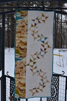 a quilt hanging on a fence in the snow