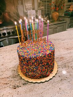 a birthday cake with candles that say happy birthday on it and sprinkles