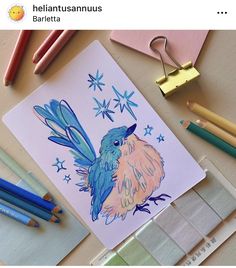 a drawing of a blue bird with stars on it's wings is surrounded by colored pencils and crayons