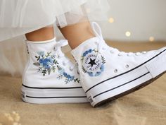 "The white Converse High Top Platform embroidered with blue flowers for the wedding was inspired by the gorgeous bridal bouquet. With many years of experience embroidering wedding shoes for the bride, this time I was really happy to receive a personalized canvas sneaker embroidery design for a very special guest. They sent me wedding photos and sweet bouquets of flowers. I love them and also love this custom embroidered item. If you also need a pair of Converse Wedding Shoes or a pair of Vans Shoes for the bride, please message me with wedding photos. I will design and embroider a special pair of wedding shoes for your wedding anniversary. * Product details: ''Converse Platform Hand Embroidered Blue Bouquets'' Shoe Type: Converse Platform Shoe color: 17. White  Price includes: Shoes + Embr Platform Shoes Converse, Blue Bouquets, Cute Converse Shoes, Unique Gifts For Girlfriend, Converse Wedding Shoes, Bridal Sneakers, White High Top Converse, Embroidered Converse, Cute Converse