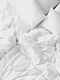 an unmade bed with white sheets and pillows