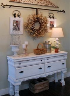 a white dresser sitting under a chandelier in a living room next to a lamp