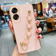 a person holding up a phone case with heart charms on it