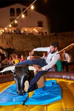 a man is riding on the back of a bull in an inflatable obstacle