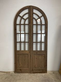 an arched wooden door with glass panels on the front and side doors are shown against a white wall