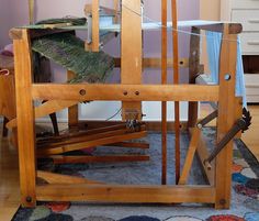 an old weaving machine sitting on top of a blue rug in front of a purple wall