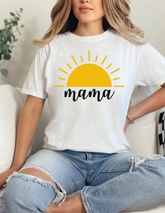 a woman sitting on a couch wearing a white shirt with the word mama printed on it