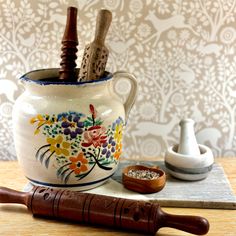 a ceramic mug with wooden spoons and salt shakers on a table next to it