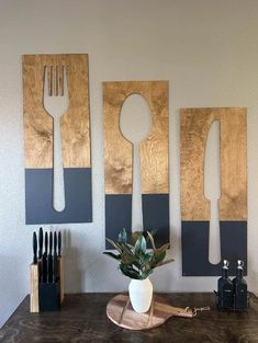 three wooden utensils hang on the wall above a table with a potted plant