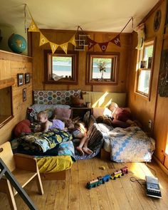 two children are sleeping on the floor in a room with wood paneled walls and windows