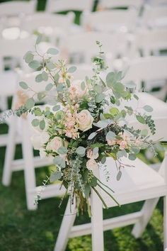 a bouquet of flowers sitting on top of a white chair in the middle of a field