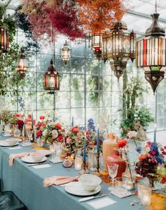 a long table is set up with flowers and candles for an outdoor wedding reception in a greenhouse